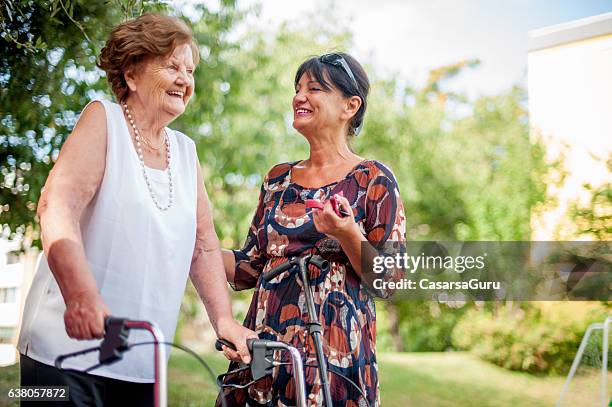 caregiver with an elderly woman outdoors - healthcare worker stock pictures, royalty-free photos & images