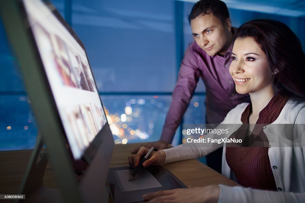 Pair of designers reviewing images on computer at night