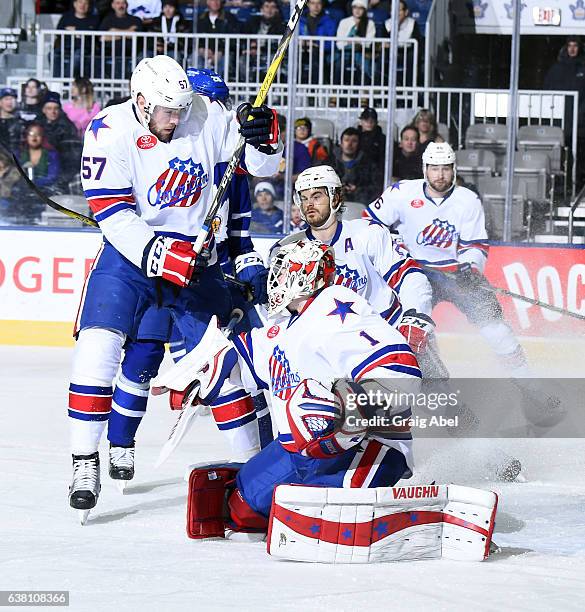 John Muse stops a shot with help from Brady Austin and Erik Burgdoerfer of the Rochester Americans during AHL game action against the Toronto Marlies...