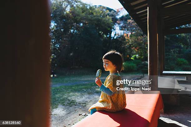 portrait of a mixed race little girl eating ice cream bar - bar girl stock-fotos und bilder