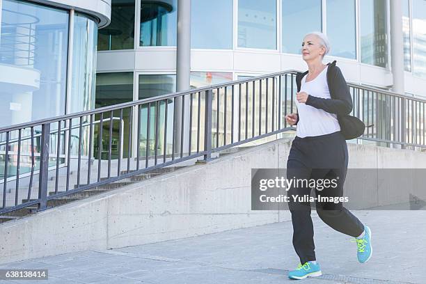 active elderly woman jogging through stuttgart - old woman running stock-fotos und bilder