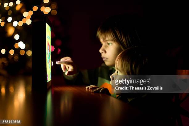 kids using a digital tablet in the dark - family game night stock-fotos und bilder