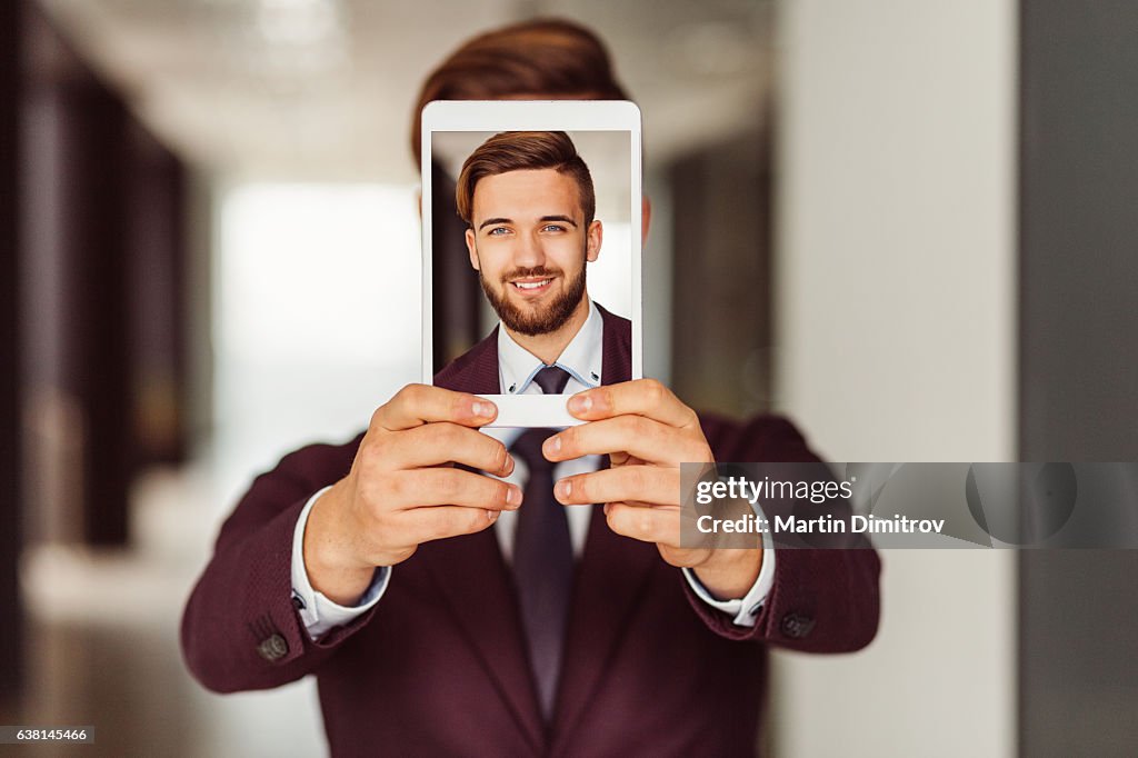 Businessman showing selfie on tablet