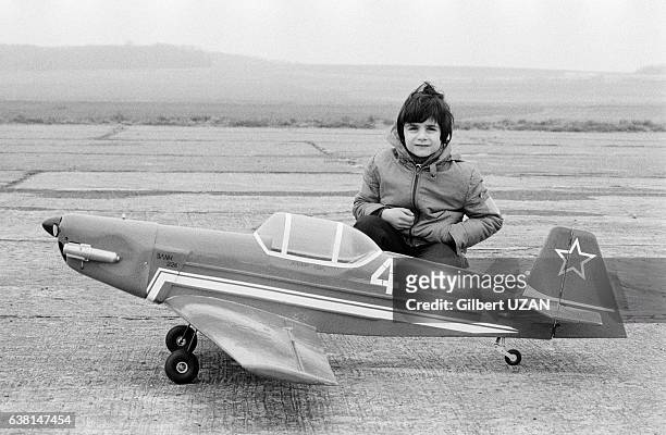 Enfant posant à côté d'un modèle réduit d'un avion en avril 1979, en France.