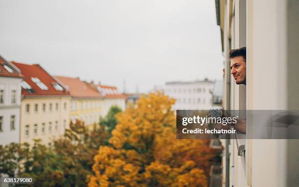 mann schaut durch wohnungsfenster in berlin prenzlauer berg - berlin mitte stock-fotos und bilder