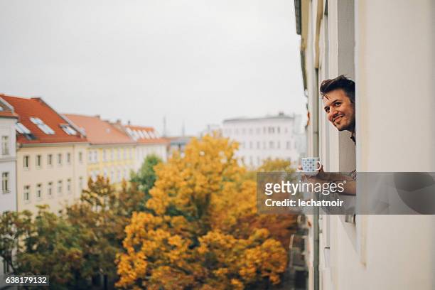mann schaut durch wohnungsfenster in berlin prenzlauer berg - residential building stock-fotos und bilder