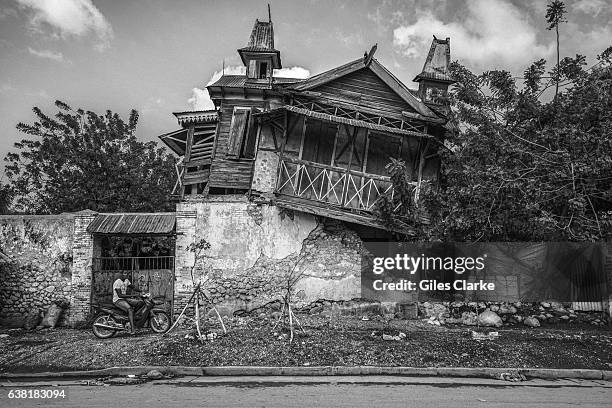 Young man on his motorcycle outside the crumbling ruin of a building in Leogane, some 25 miles from the Haitian capital of Port-Au-Prince. Following...