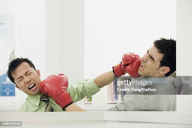 paar bürokollegen kämpfen mit boxhandschuhen im büro - funny boxing stock-fotos und bilder