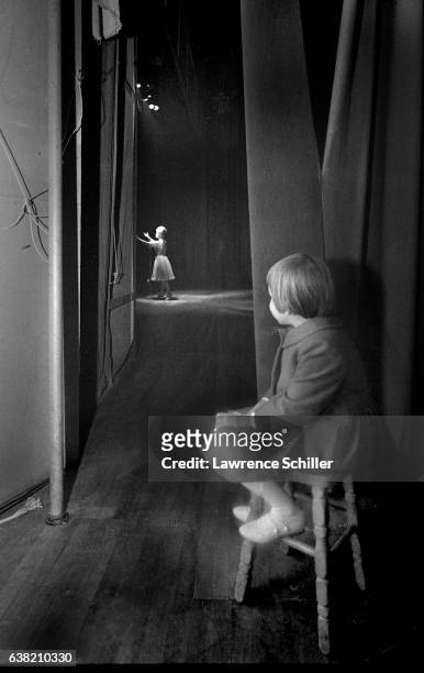 Six-year-old child Carrie Fisher sits on a stool behind a curtain and watches as her mother, actress Debbie Reynolds , performs on stage at the...