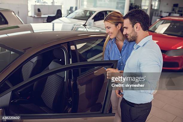 一緒に新しい車を見て車のディーラーで若いカップル。 - buying car ストックフォトと画像