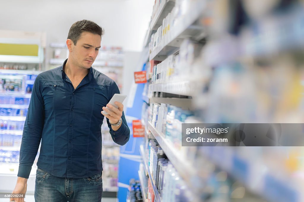 Mann mit Smartphone im Supermarkt