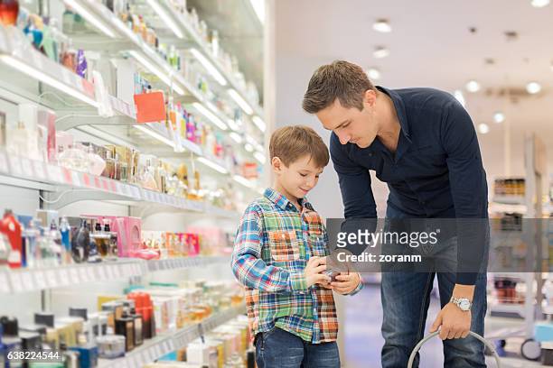 father choosing perfume with son - choosing perfume stock pictures, royalty-free photos & images