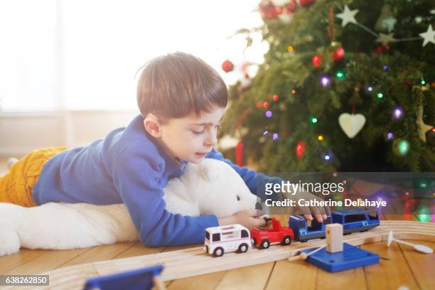 a boy playing in front of the christmas tree - christmas toys stock pictures, royalty-free photos & images
