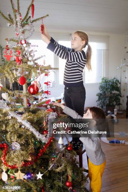 A girl and her little brother decorating the Christmas tree