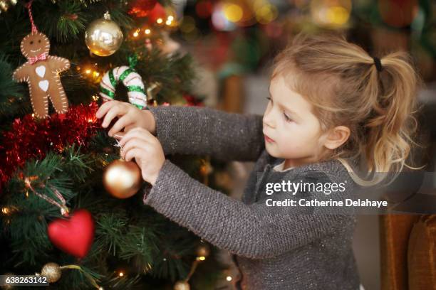 A little girl holding a Christmas tree bauble