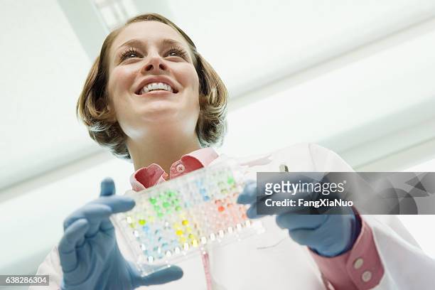 scientist holding medical samples in laboratory - one young woman only health hopeful stock pictures, royalty-free photos & images