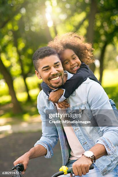 father and daughter riding a bike together. - family vertical stock pictures, royalty-free photos & images