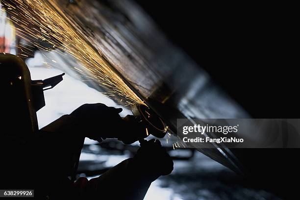 soldador trabajando con amoladora en el lado del casco de un barco - astillero fotografías e imágenes de stock
