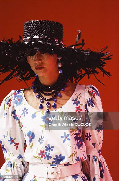 Un modèle porte une robe à motif fleuri et un immense chapeau de paille noir avec un collier lors du défilé Yves Saint Laurent Printemps/Eté le 18...