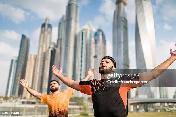 fitness friends stretching and looking up in dubai marina - yoga office arab stock pictures, royalty-free photos & images