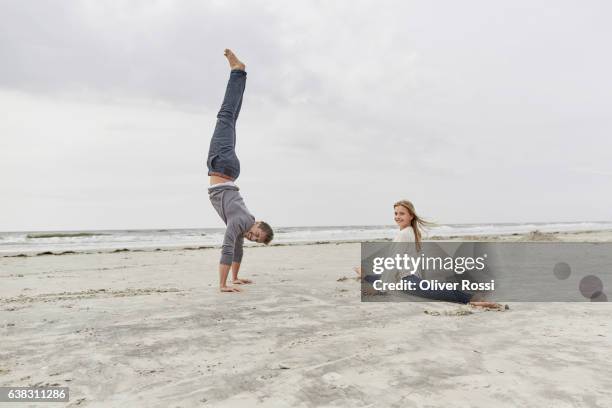 father with daughter doing a handstand on the beach - jeans barefoot girl stock pictures, royalty-free photos & images