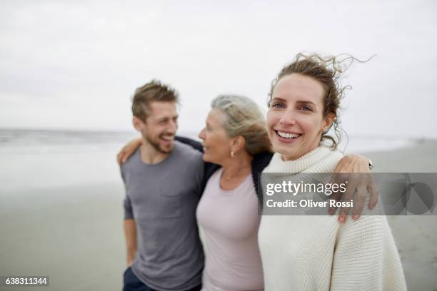 happy couple with senior woman on the beach - family trip in laws stock pictures, royalty-free photos & images