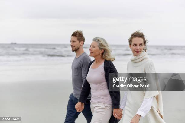 couple with senior woman walking on the beach - sogra imagens e fotografias de stock