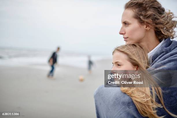 mother hugging daughter on the beach - mother daughter towel fotografías e imágenes de stock