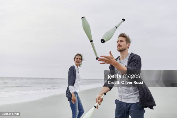 man juggling with juggling clubs on the beach - juggler stock-fotos und bilder