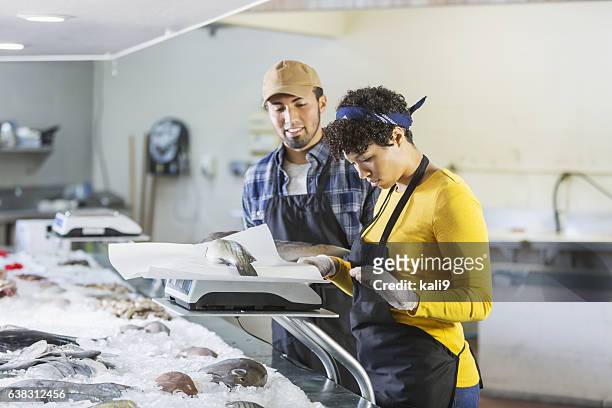 young mixed race couple working in fish market - fishmonger stock pictures, royalty-free photos & images