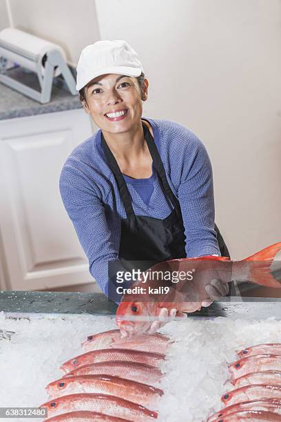 mujer mestiza que trabaja en el mercado de pescado, sosteniendo pargo - pescadero fotografías e imágenes de stock