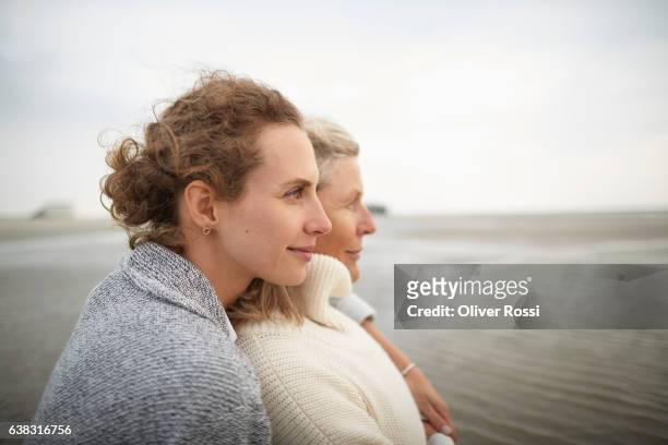 adult daughter hugging mother on the beach - daughter bildbanksfoton och bilder