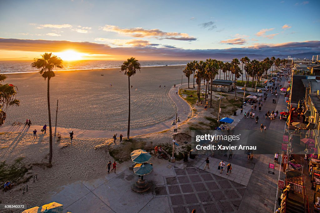 Tourists walking on footpath by beach during sunset