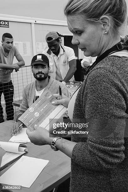 volunteer checking food cards in refugee camp dinner line - quiosque stock pictures, royalty-free photos & images