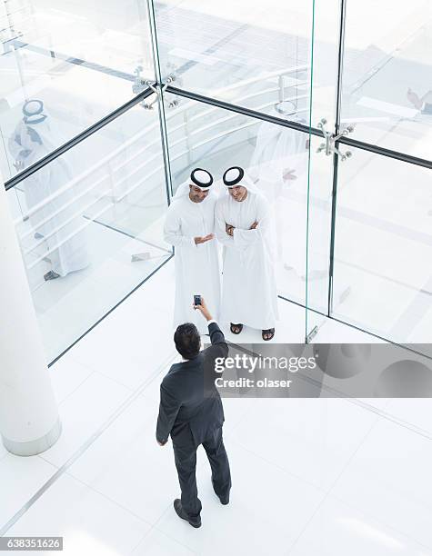 three arab business men taking a picture - lypseuae2015 stock pictures, royalty-free photos & images