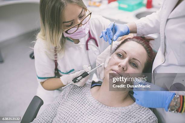 kosmetologe macht botox-injektion - surgeon holding needle stock-fotos und bilder