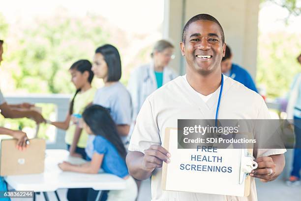 african american male nurse promotes community health fair - health fair stock pictures, royalty-free photos & images