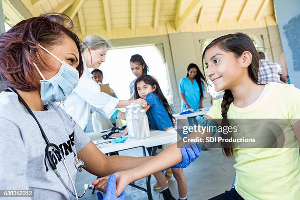 volunteer doctor prepares to draw blood from a preteen girl - health fair stock pictures, royalty-free photos & images