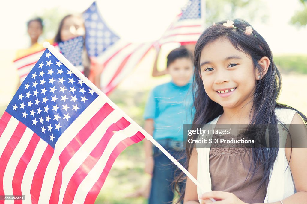 Süße philippinische Mädchen hält amerikanische Flagge im Freien