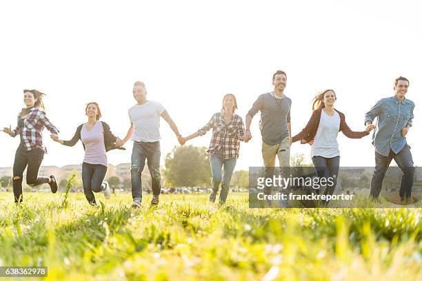 group of people running on the park at dusk - community arm in arm stock pictures, royalty-free photos & images