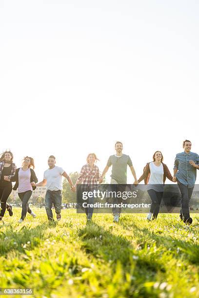 group of people running on the park at dusk - community arm in arm stock pictures, royalty-free photos & images