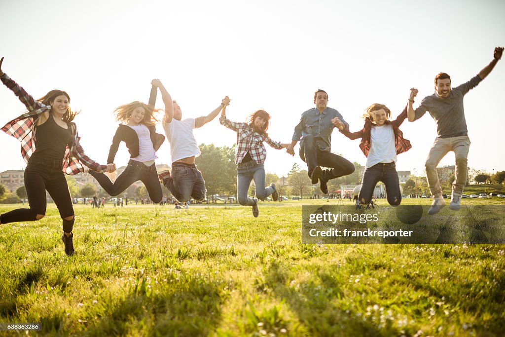 Group of people jumping on the park at dusk