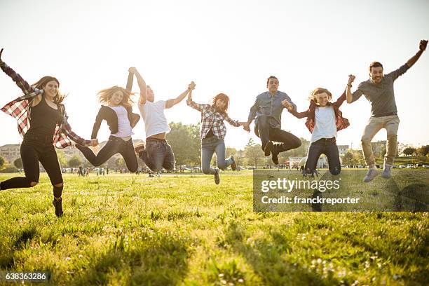 group of people jumping on the park at dusk - jump joy stock pictures, royalty-free photos & images