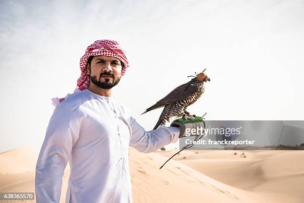 jeque árabe en el desierto sosteniendo un halcón - cetrería fotografías e imágenes de stock