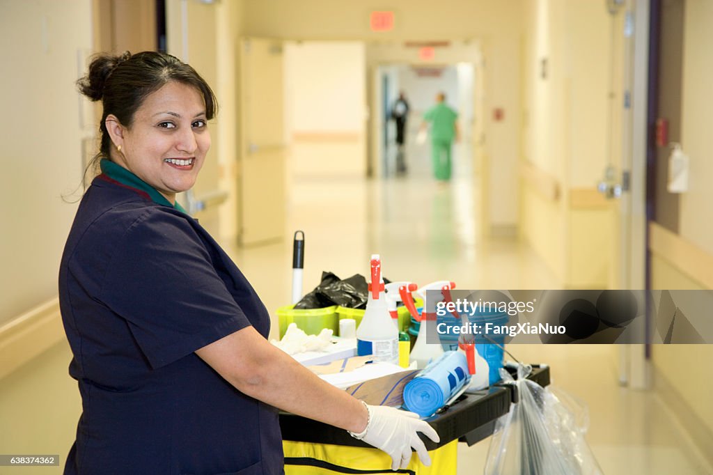 Custodian janitor in hospital hallway with cart