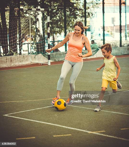 mom and son playing football on stadium - soccer mum stock pictures, royalty-free photos & images