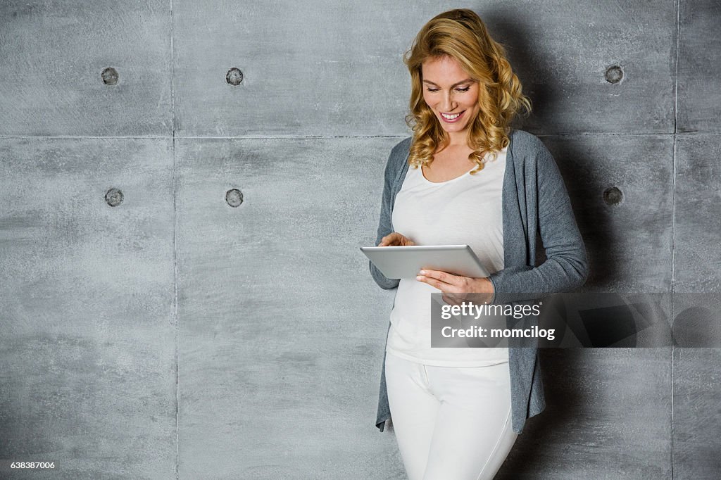 Beautiful female standing with tablet and smiling