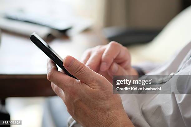 asian senior man is typing text on smart phone. - japanese people typing stock pictures, royalty-free photos & images