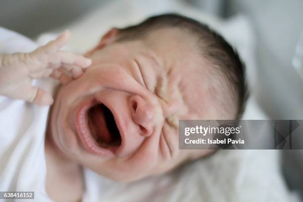 Newborn baby crying in hospital crib. First day