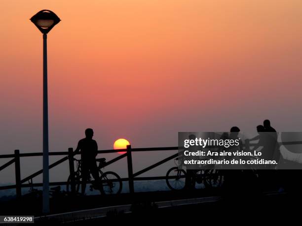 people on bicycle at sunset - silueta stockfoto's en -beelden